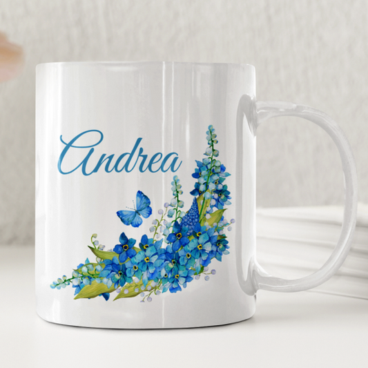Vit keramikmugg med motiv av blå blommor och en fjäril samt ett personligt namn- DalaStil