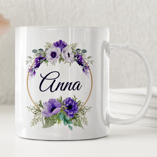 Vit keramikmugg med en lila blomkrans i akvarell och ett personligt namn i mitten.